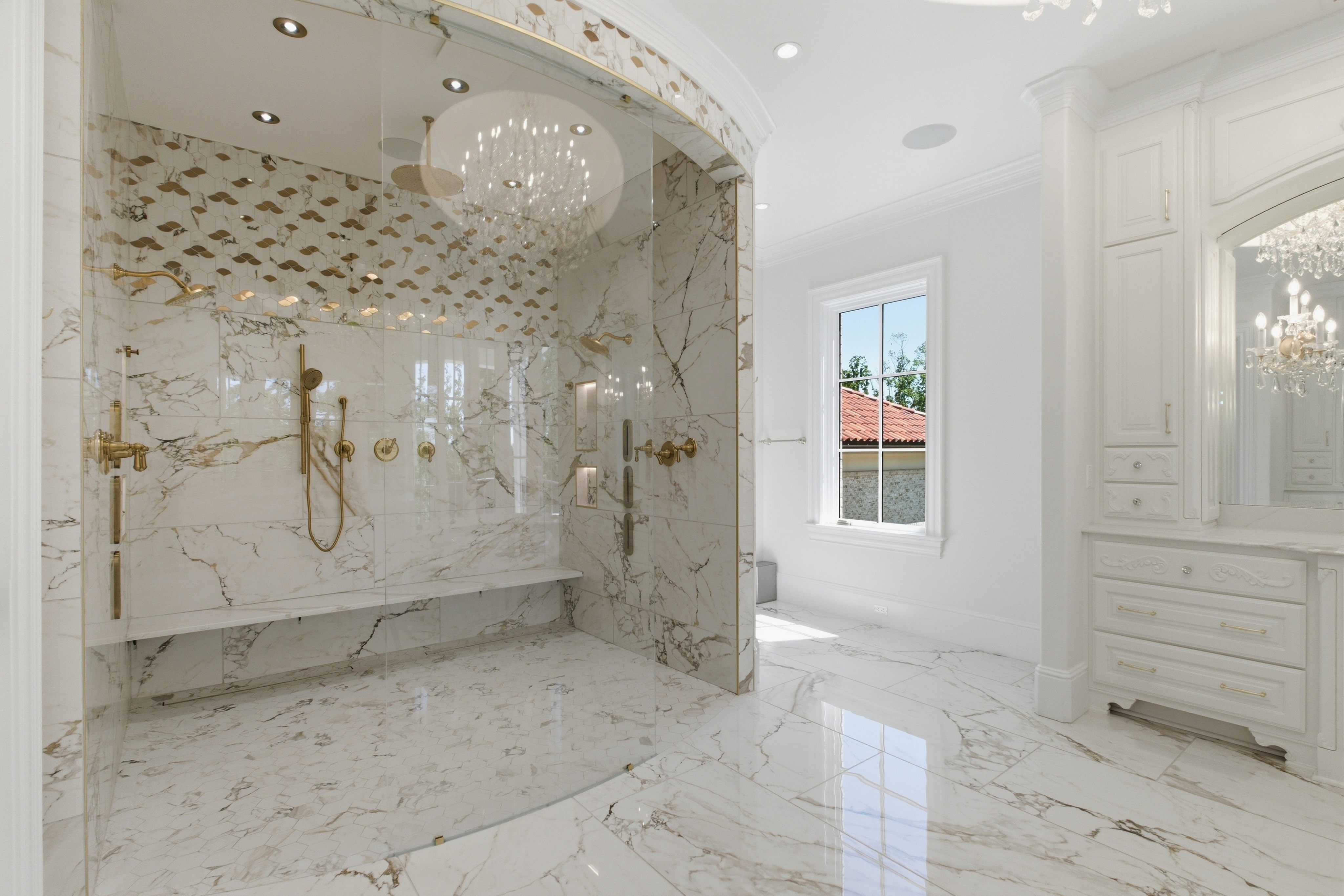 Primary bath walk-in shower with book-matched marble and gold fixtures